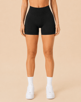 Mujer con shorts deportivos negros de cintura alta y calcetines blancos, vista frontal