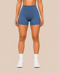Mujer con shorts deportivos azul acero de cintura alta y calcetines blancos, vista frontal